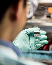 Scientist holding vial labeled electrolytes
