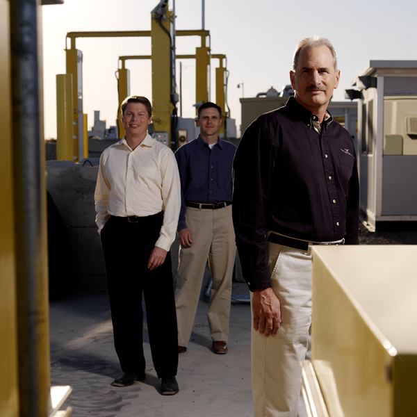 three researchers stand outdoors among radiation detection devices