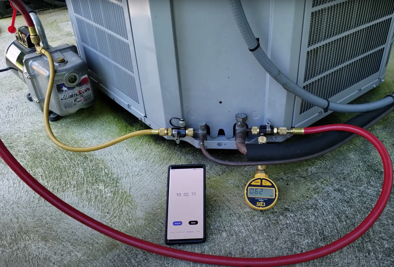 A smartphone device next to an air conditioning unit with two hoses attached
