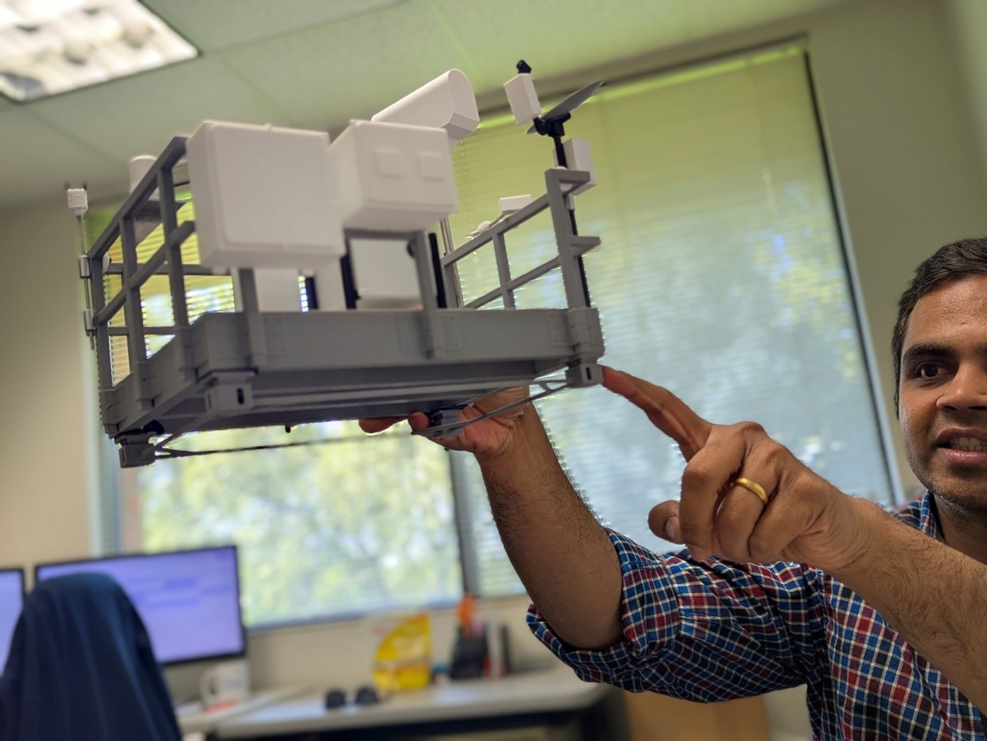 Krishnamurthy explains the BEACONS atmospheric sensor array setup using a miniature model.