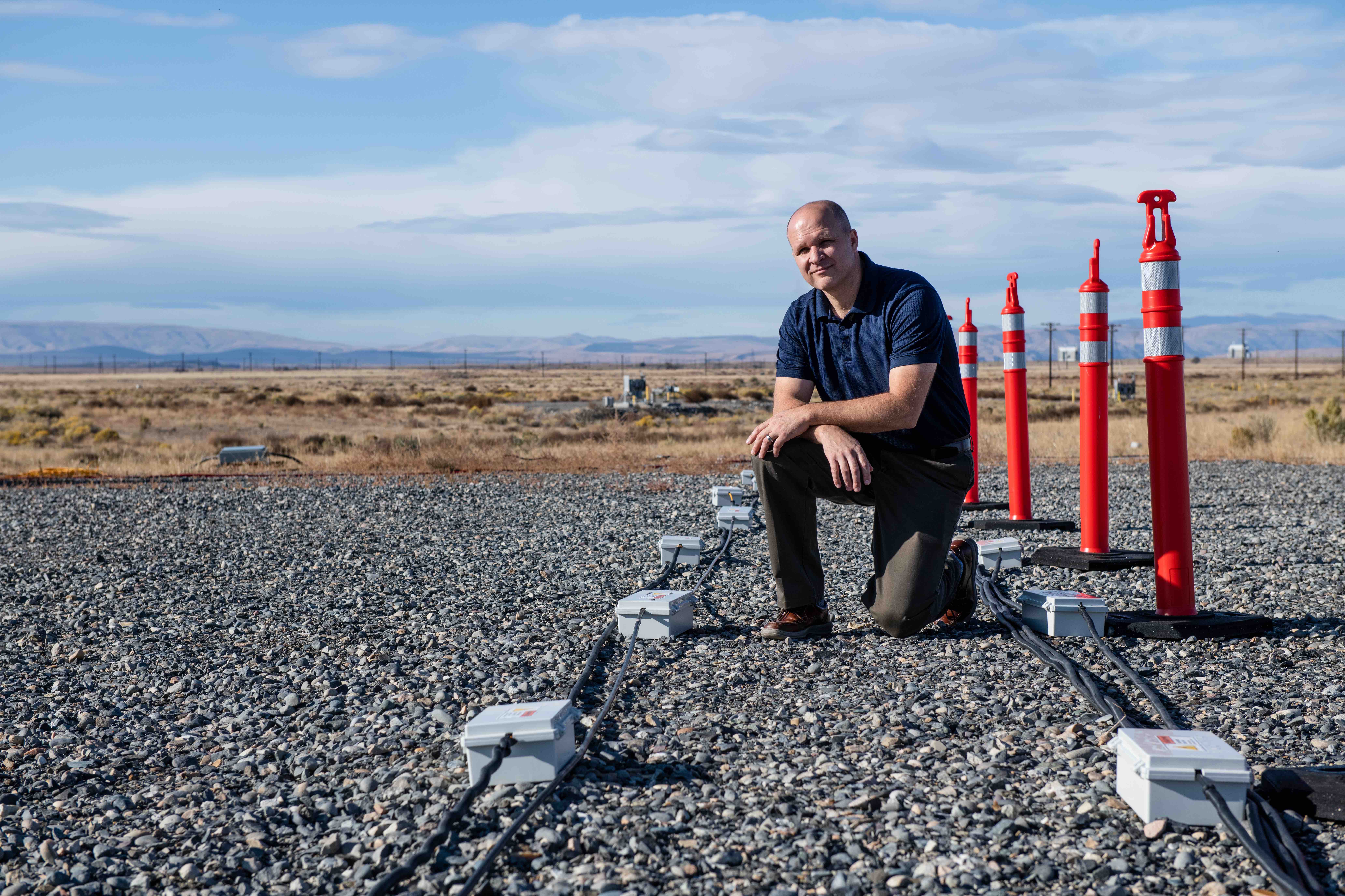 Computational scientist Tim Johnson kneels next to electrical resistivity tomography (ERT) cables and spikes used to monitor subsurface contaminants in the desert-like Hanford 100 Area. 