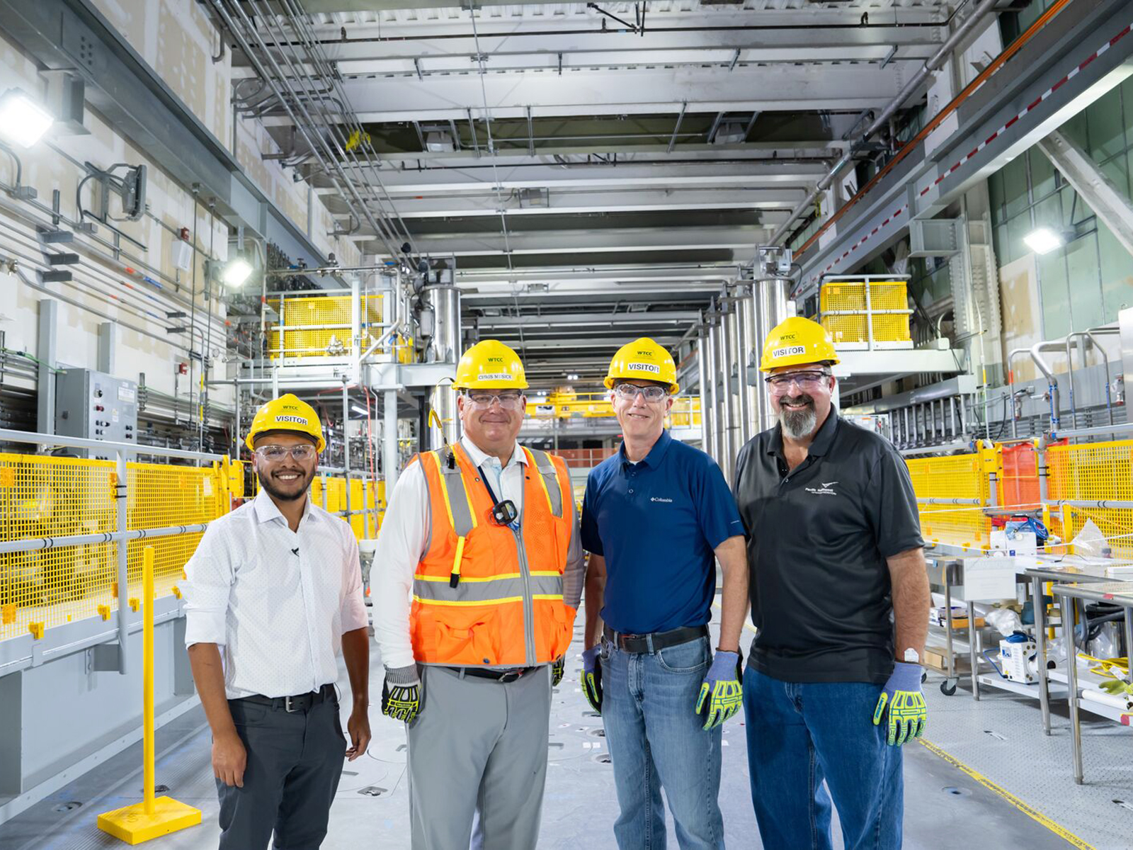 Three PNNL researchers, Jos&eacute; Marcial (left), John Vienna (second from right), and Will Eaton (right) standing in the Waste Treatment and Immobilization Plant with Bechtel National's Chris Musick (second from left.) They are all wearing safety eyewear and hardhats.