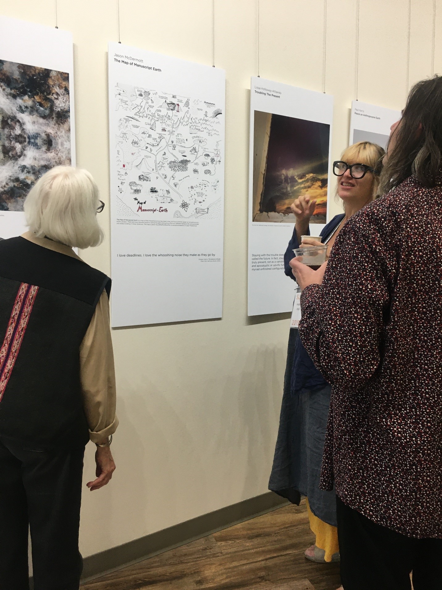 Photo of Map of Manuscript Earth and attendees discussing poster