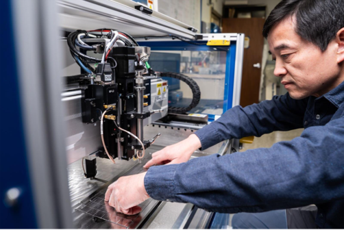 Person reaching his hands into a advanced acoustic microscope to adjust it