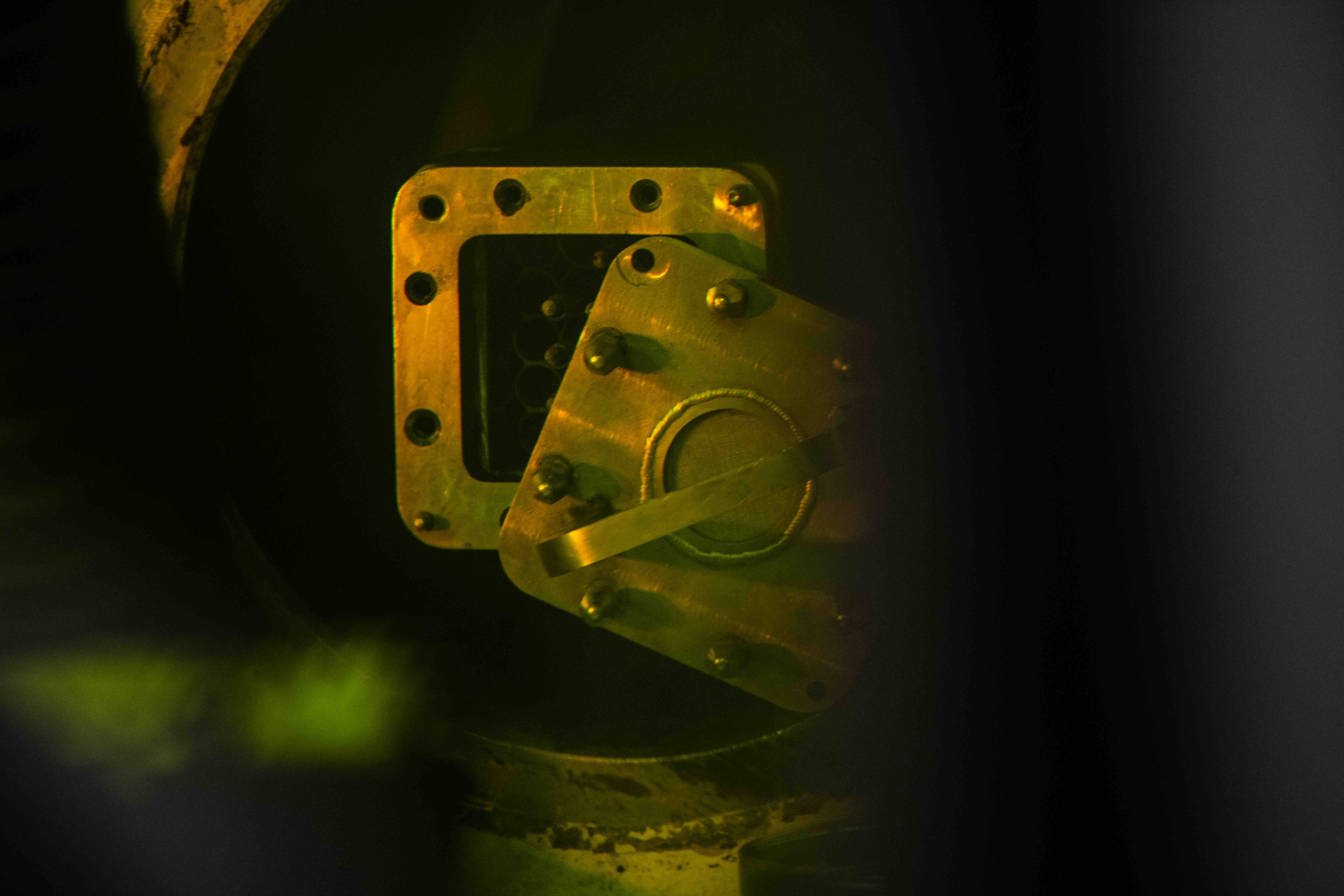 A square lid is partially removed from a metal canister. Inside, the tips of several nuclear fuel rods peek out of the canister.