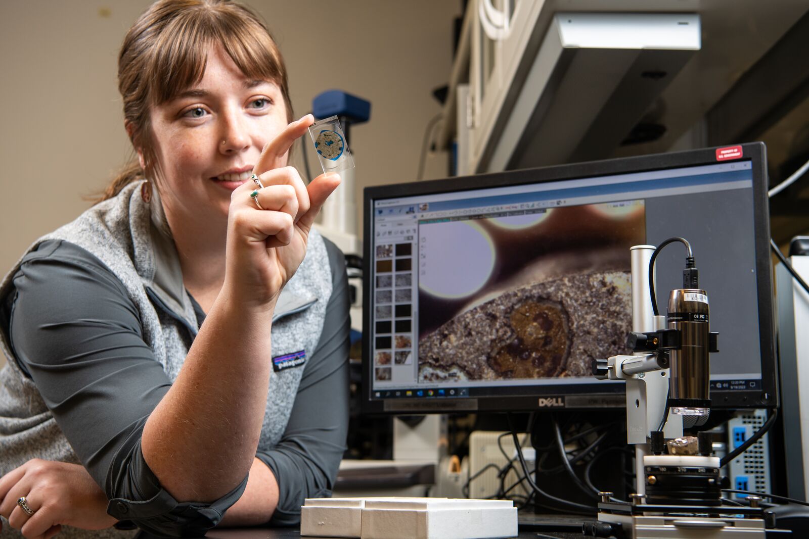 Photo of Emily Nienhuis holding a petographic thin section of a Wallula pilot study basalt sample