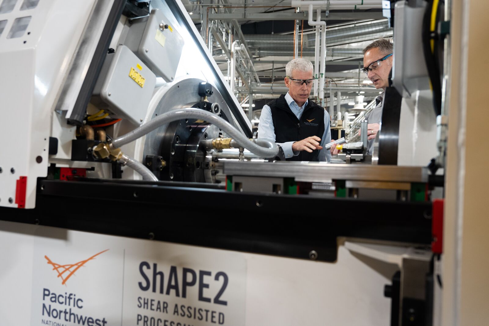 DOE Secretary Chris Wright, wearing safety glasses, being given tour of PNNL's Shear Assisted Processing and Extrusion machine.