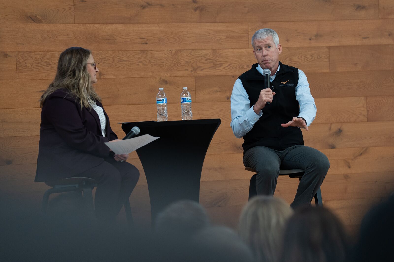 DOE Secretary Chris Wright on stage, holding a microphone, speaking to an audience.