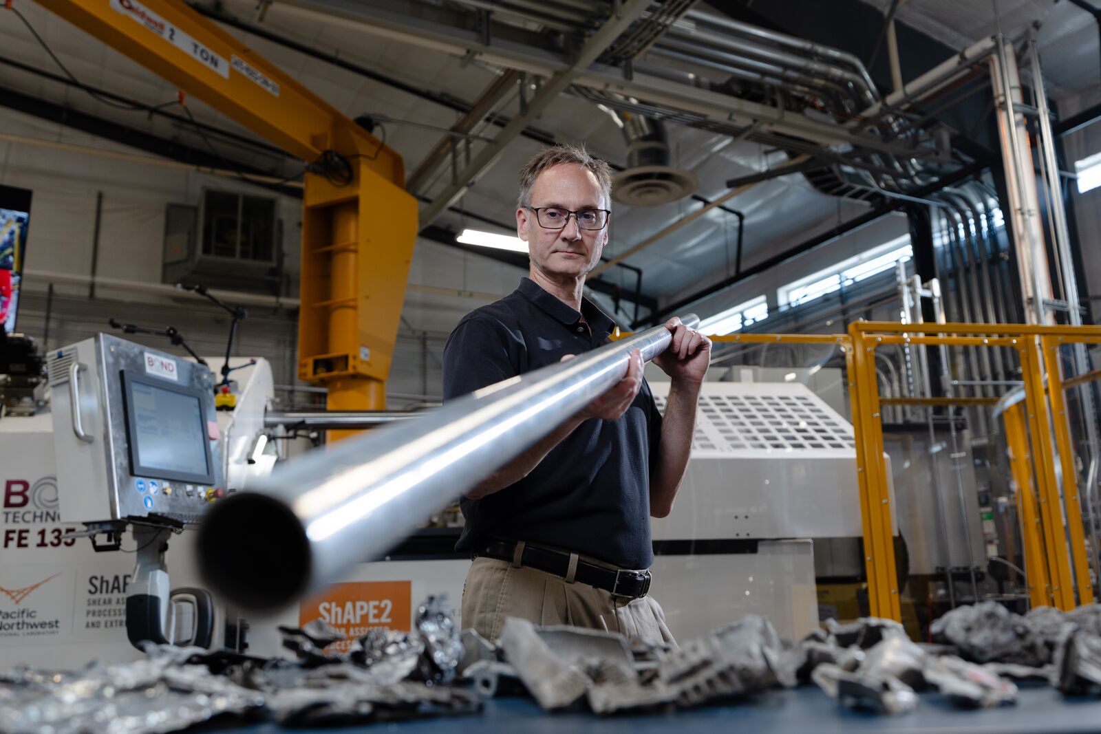 A man stands holding a long metal tube