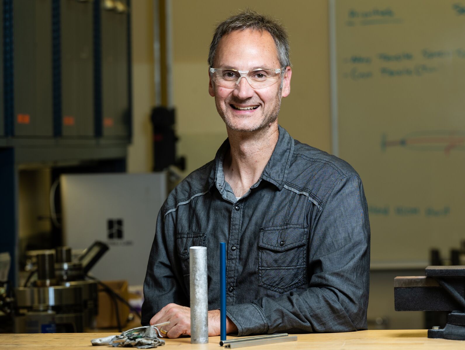 Photo of PNNL Materials Scientist Scott Whalen at a table, wearing safety goggles.