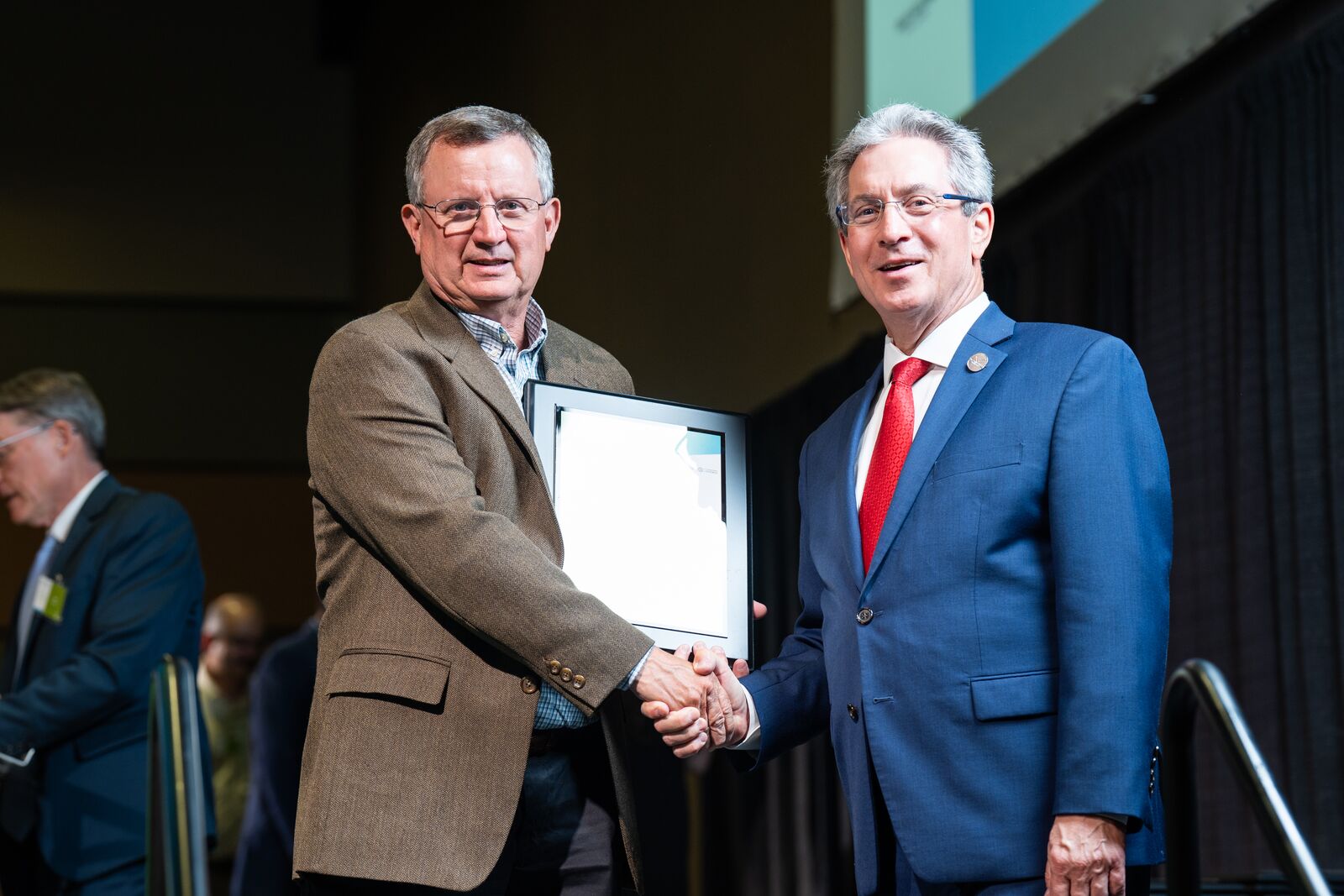 Two men holding a plaque and shaking hands