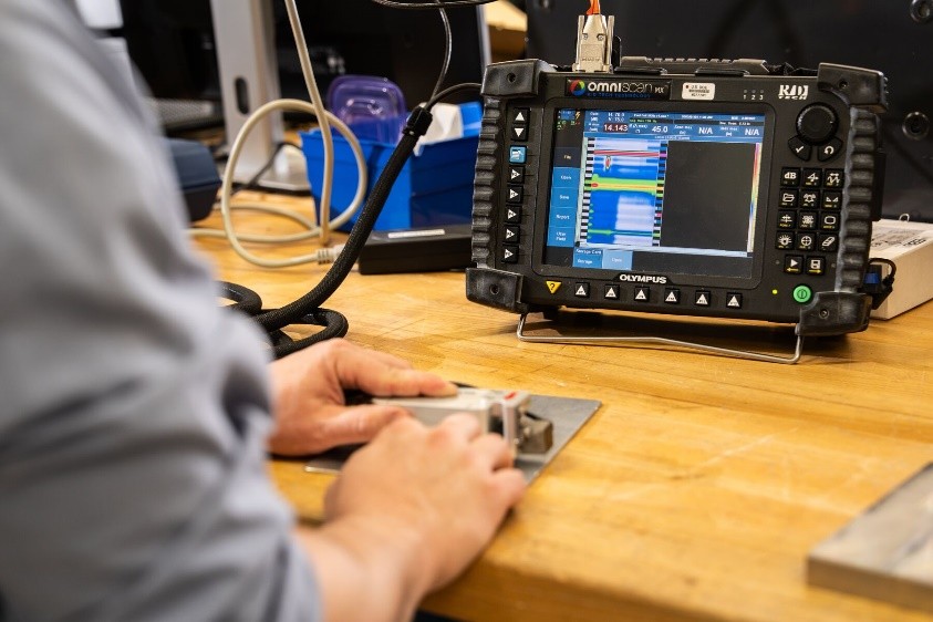 Nondestructive Evaluation machine being used on a piece of metal material on a counter in a lab setting