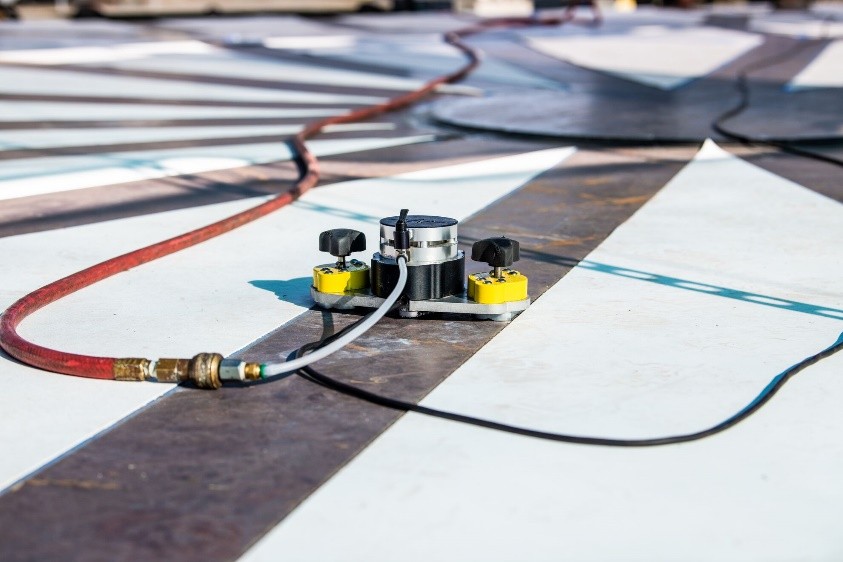 Small robotic device on white and black floor with wires 