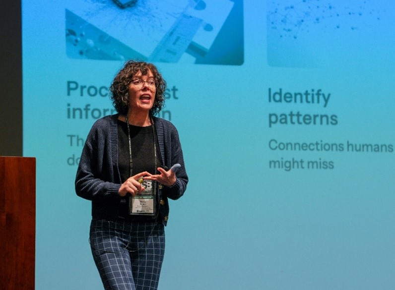 Nancy Washton speaking in front of a large screen