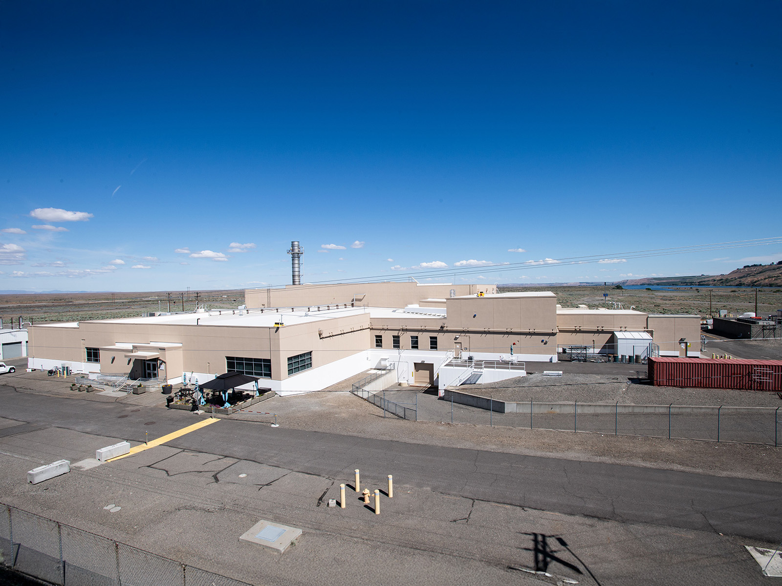 the exterior of a low, blocky white building with glass windows and a concrete driveway