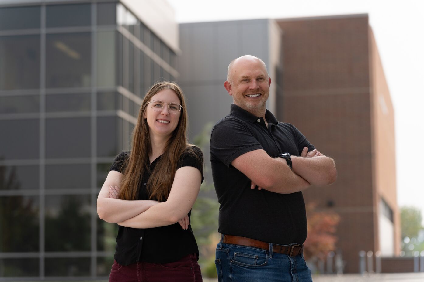 Jenna Pope is on the left; Ben Kowash is on the right. Each has their arms crossed; they stand outside on the PNNL campus.