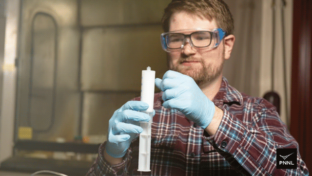 Gif of a white man holding a large syringe filled with opaque liquid