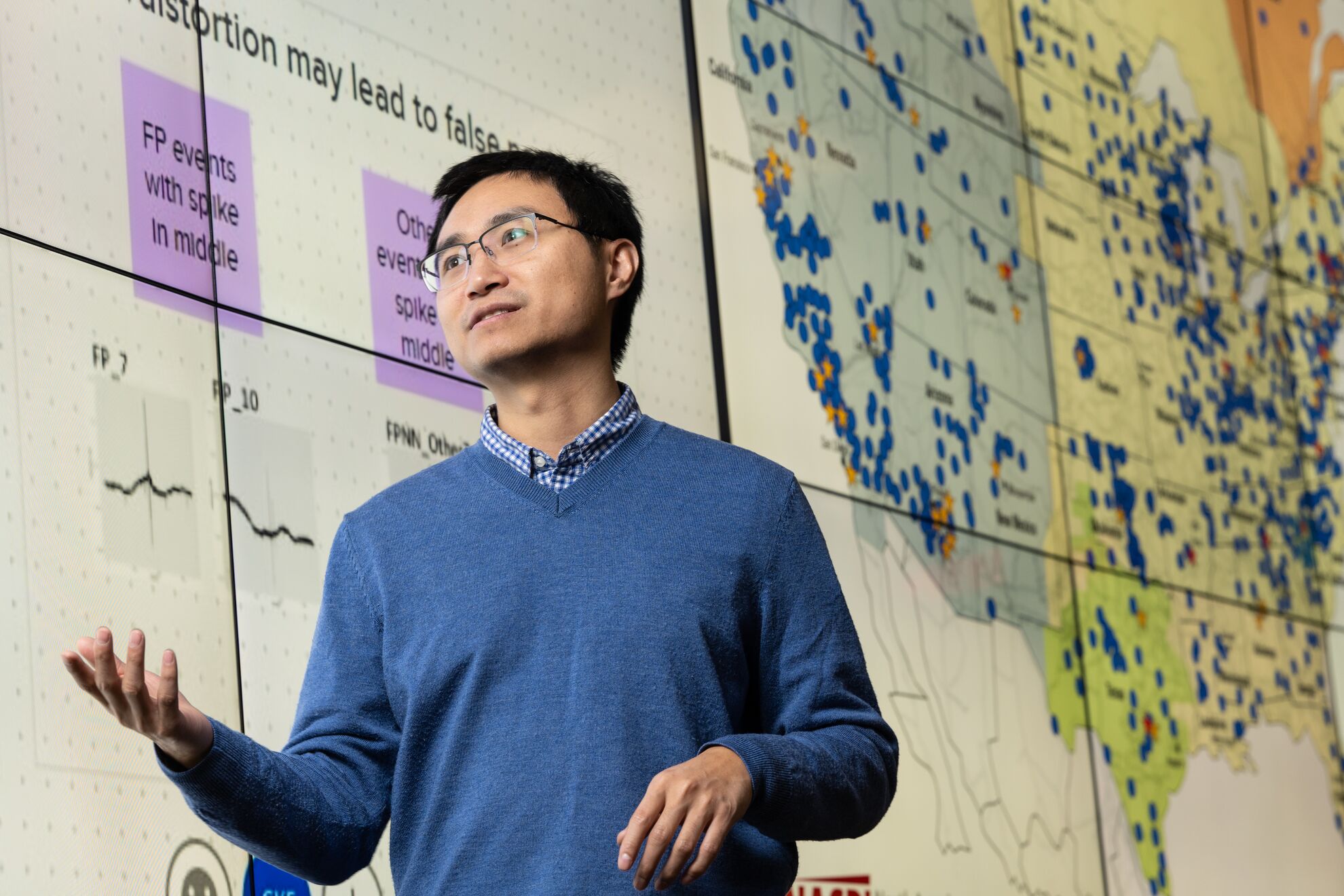 Photo of researcher Tim Yin in front of a large board showing the nation's electric grid and their analyses of machine-learning confidence scores.