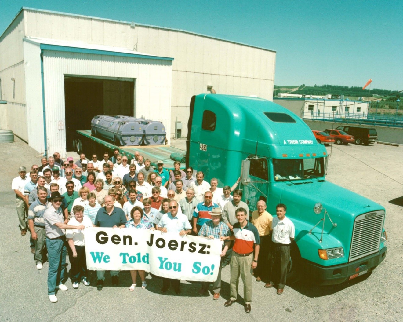 Photo of PNNL and sponsor staff holding a banner in front of a green-blue semi-truck.