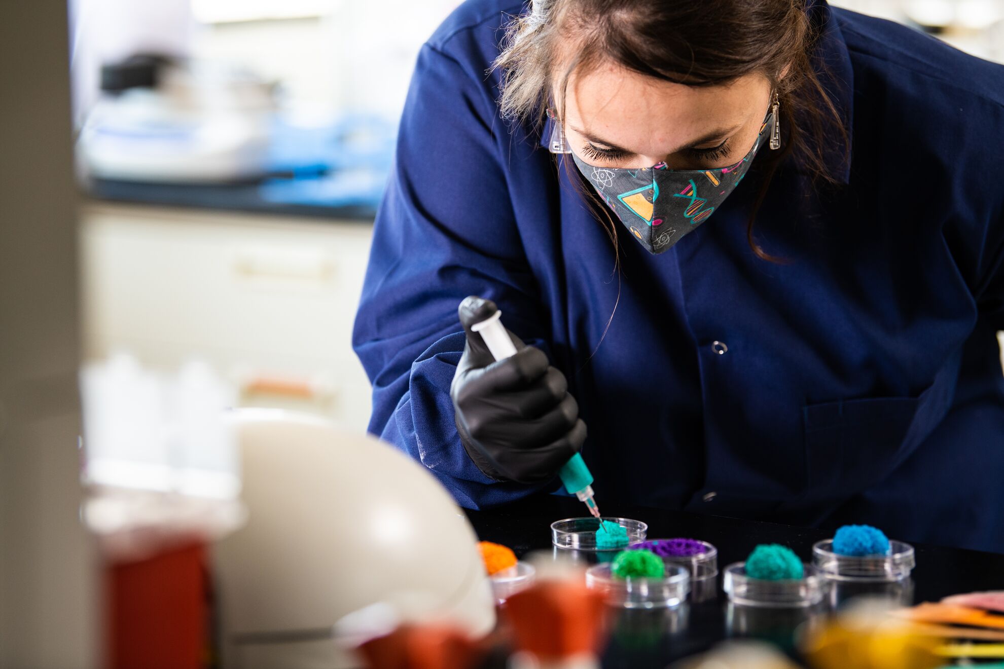 Female in lab coat injecting colors into container