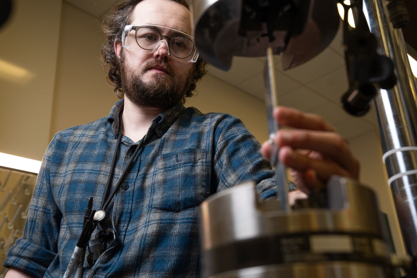 A man stands looking over a manufacturing instrument