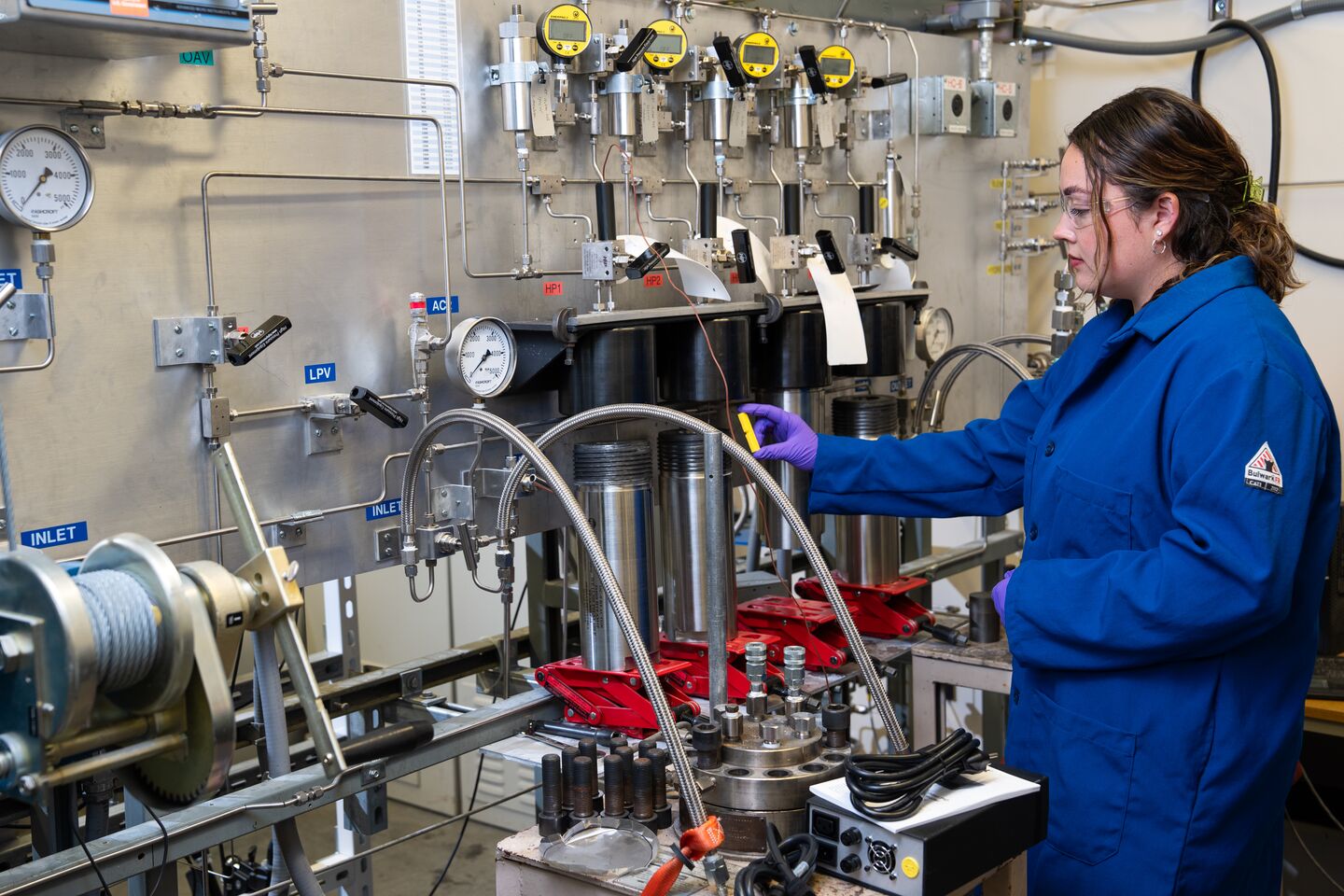 A researcher in a lab coat places a material sample into specialized testing equipment.