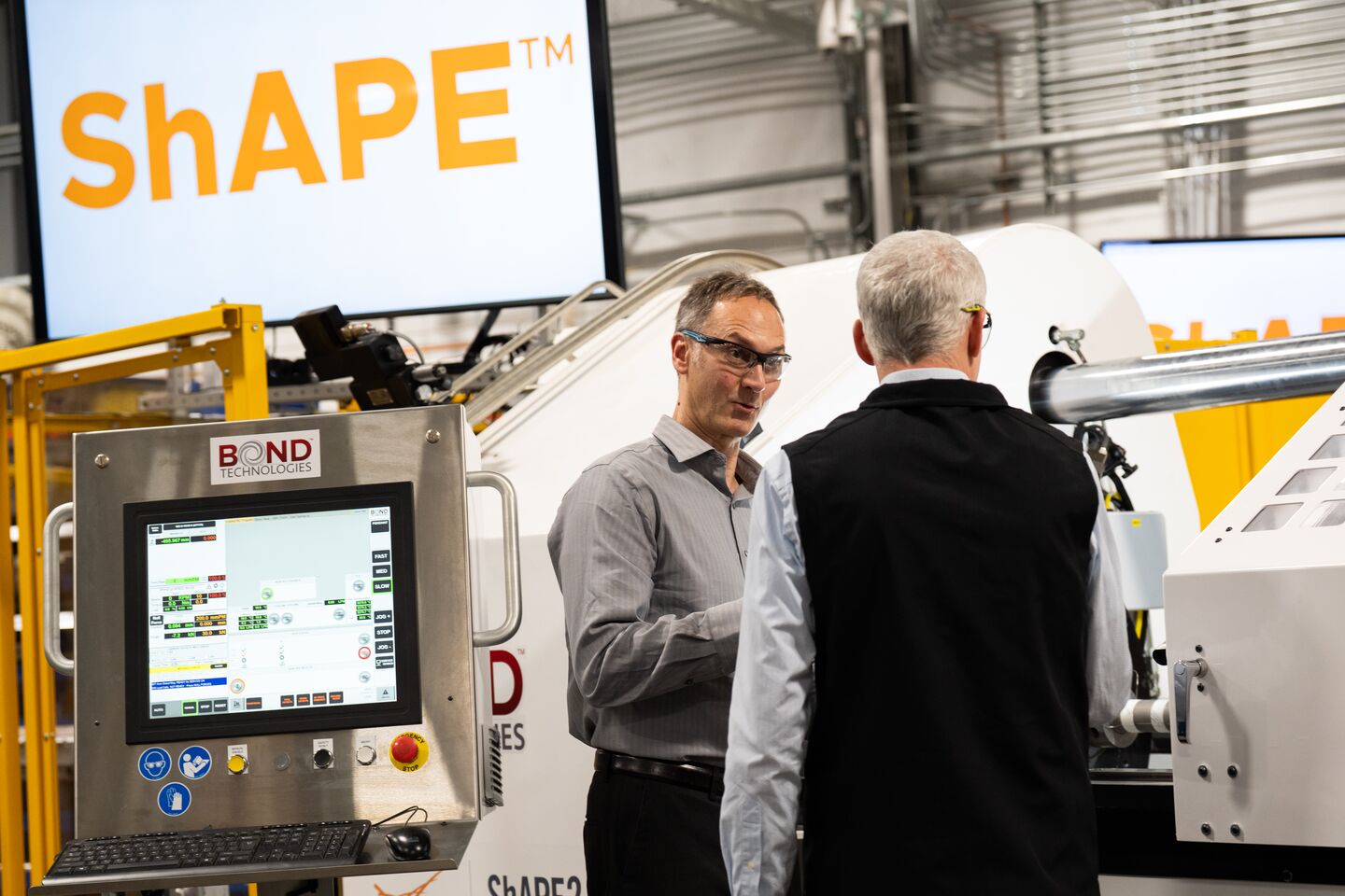 Secretary of Energy Chris Wright talks to a researcher in safety goggles beside ShAPE equipment