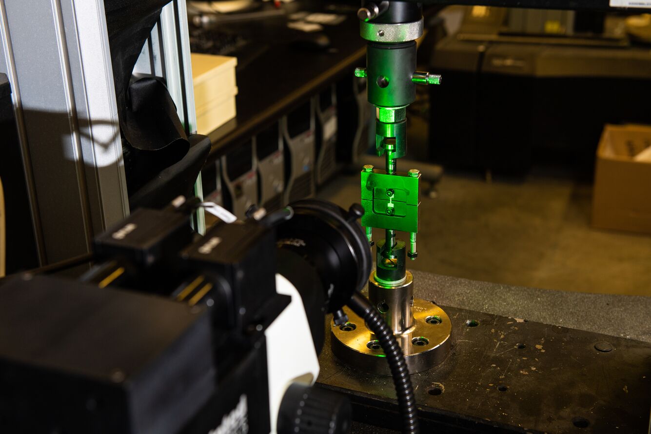 A testing apparatus in a materials science lab, to test samples while taking photographs to enable vulnerable locations within sample areas of interest.