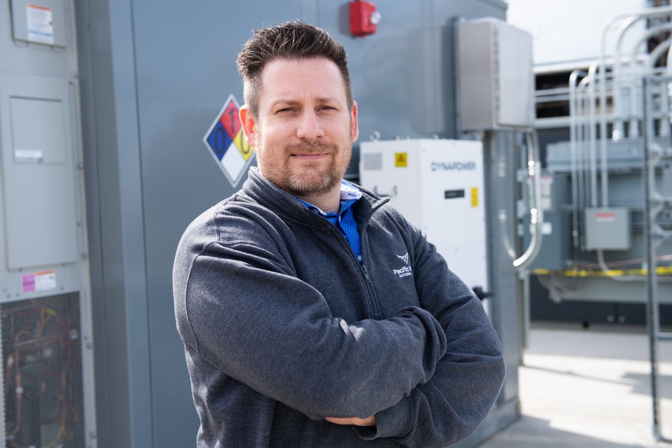 man with gray sweatshirt standing in front of equipment