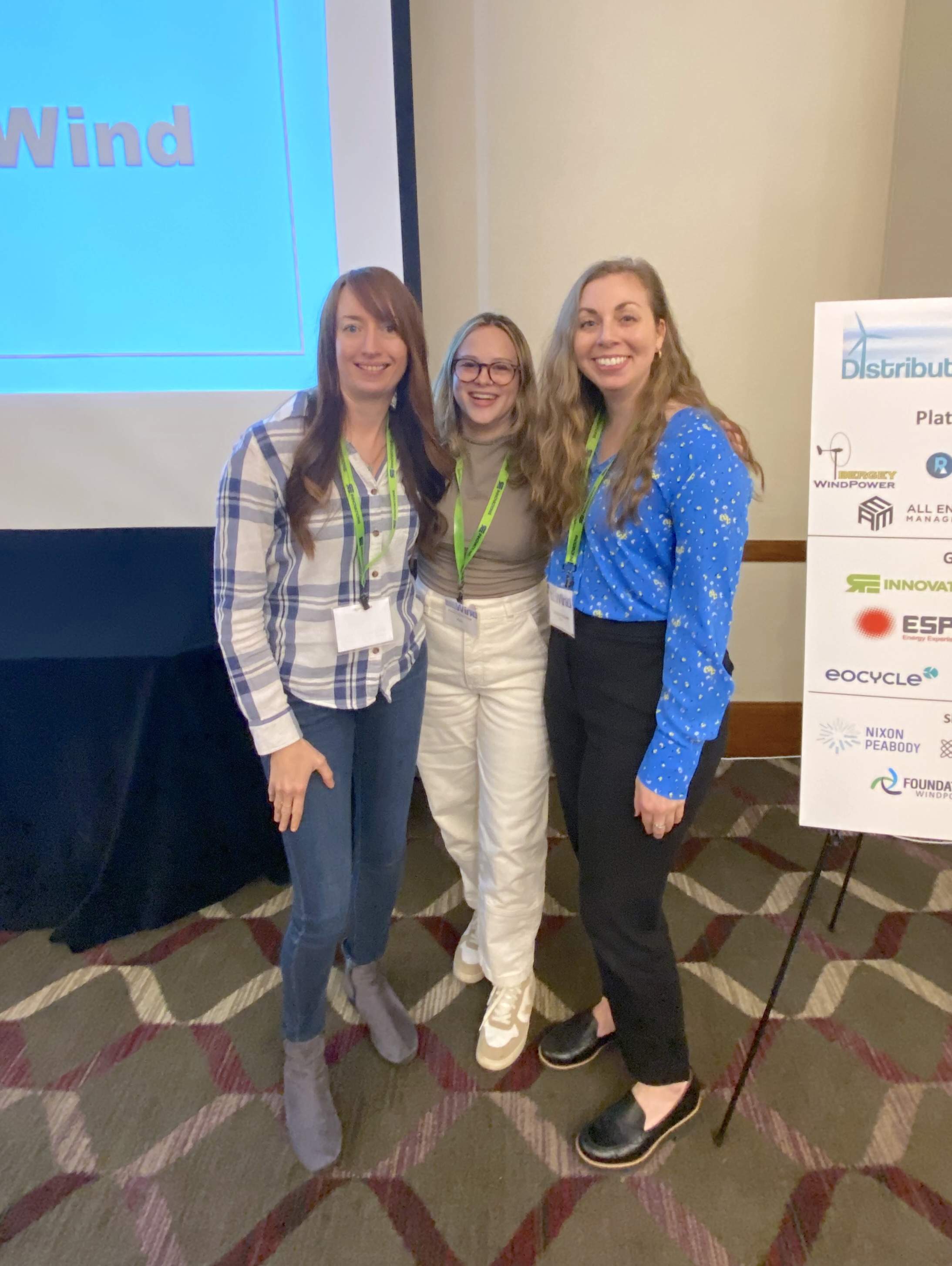 Three people standing next to a poster at a conference