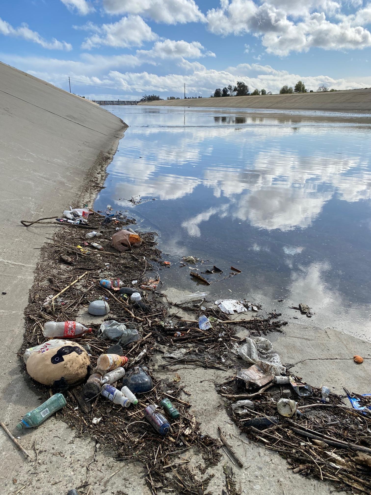 plastic debris collected at the edge of a canal connected to the Los Angeles River