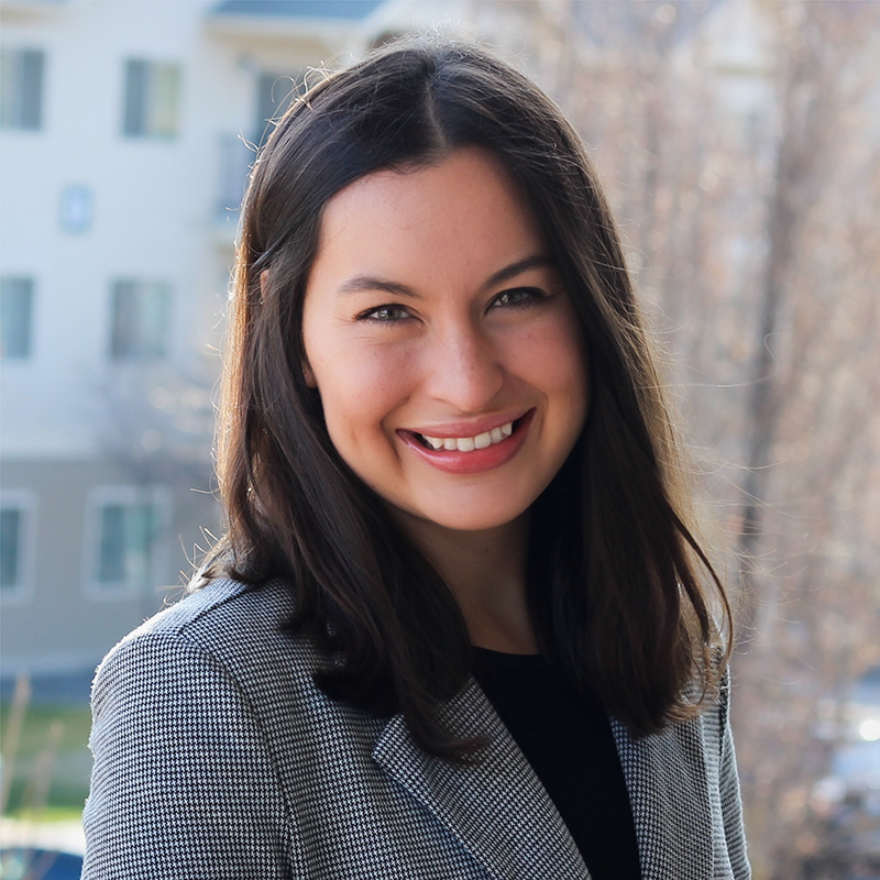 a smiling person with dark hair pictures from the shoulders up