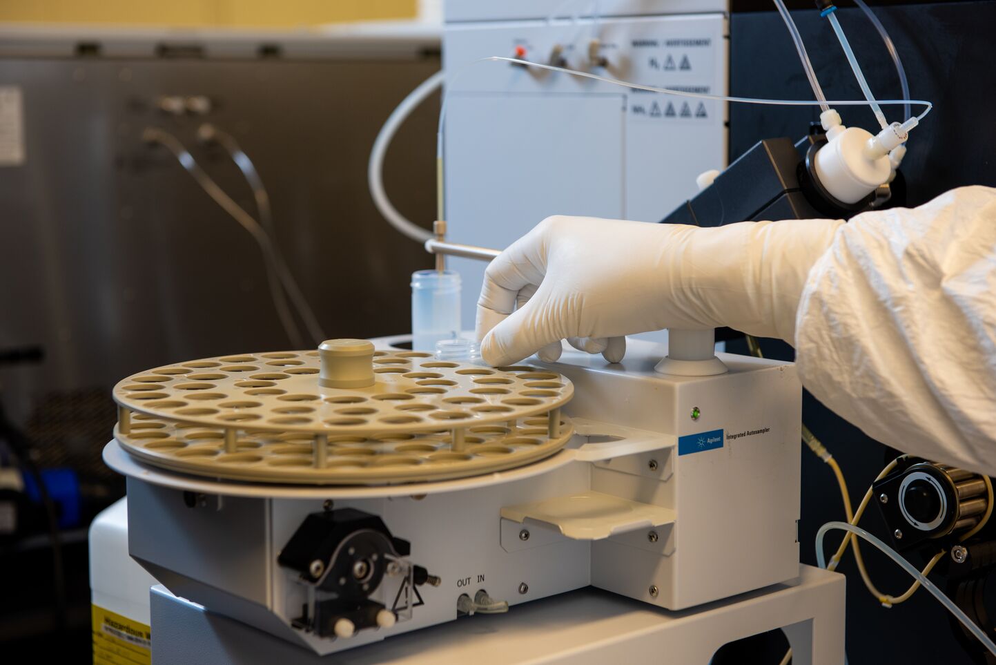 A gloved hand lifting a vial of material from a testing device