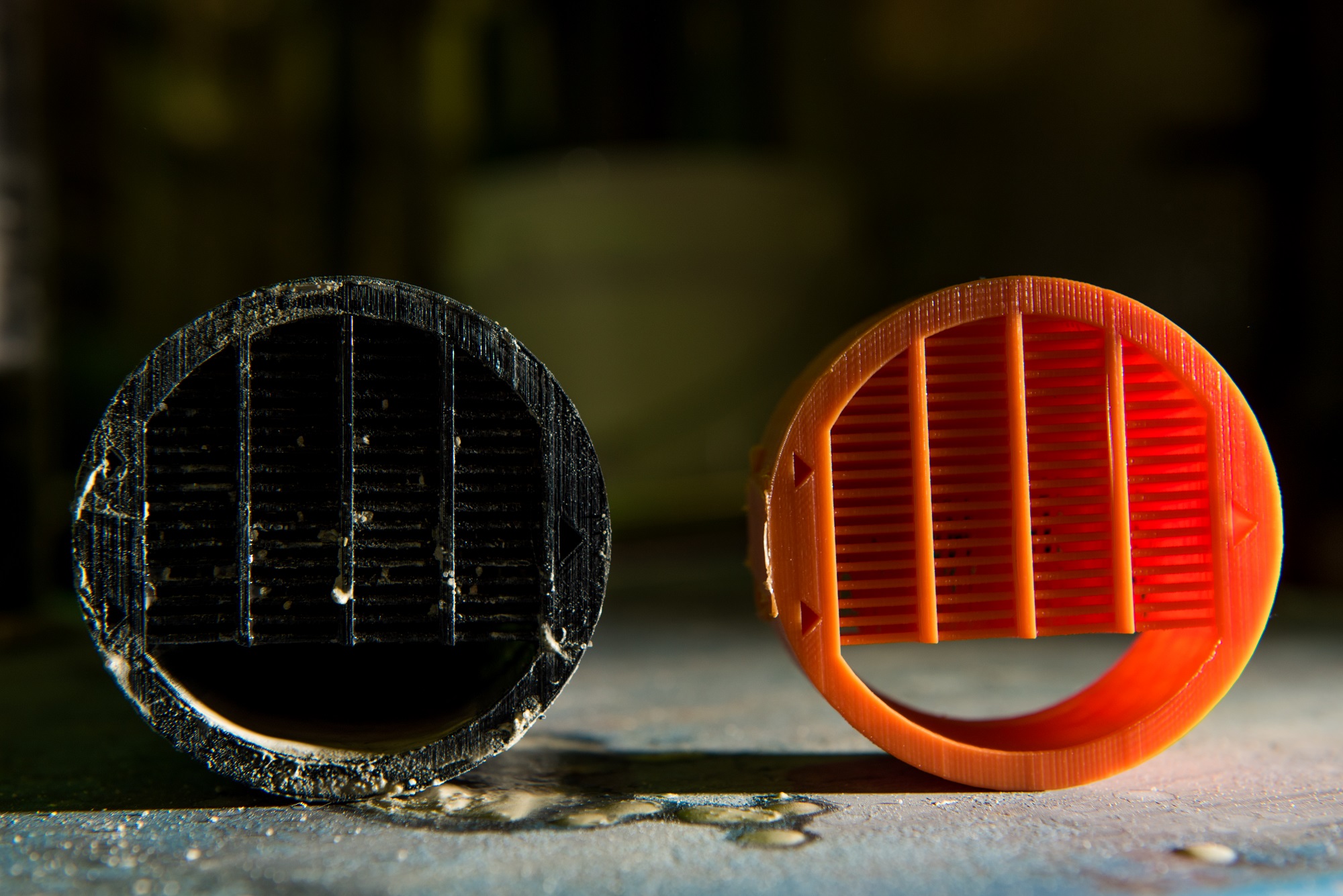 Closup of two separator pucks (one black, one orange), showing how the pattern of posts inside sort out particles