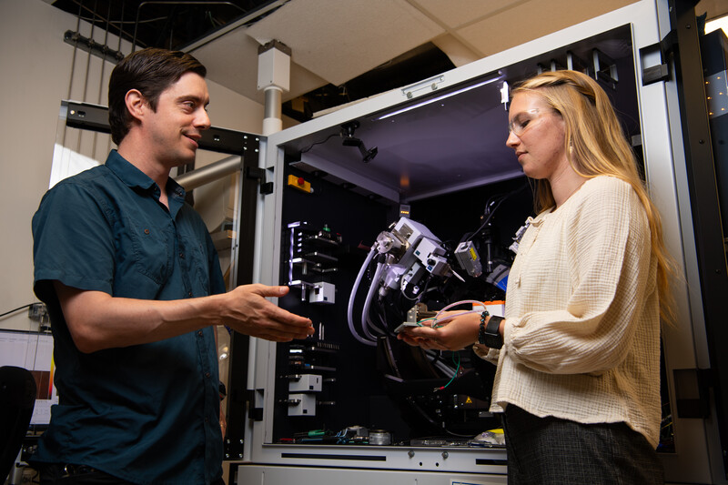 Quin Miller speaks to Madeline Bartels in front of an X-Ray diffractor