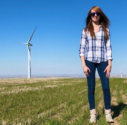 Woman with long hair standing in front of wind turbine