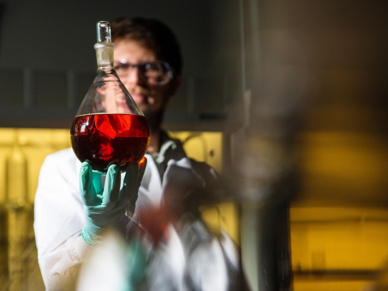 Picture of a researcher holding a large flask filled with red liquid