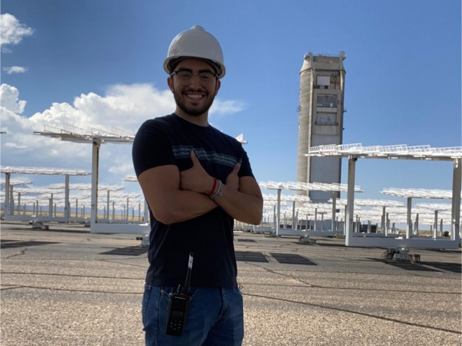 Cesar Moriel, a student from the University of Texas at El Paso, stands with his arms crossed, smiling, and wearing a hard hat.