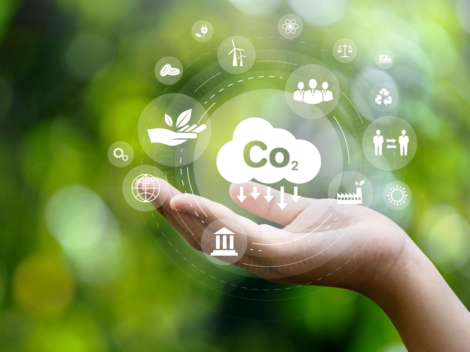 Digital image of a hand holding bubbles that contain various icons. These include icons for carbon dioxide reduction, recycling, wind energy, solar energy, and more.