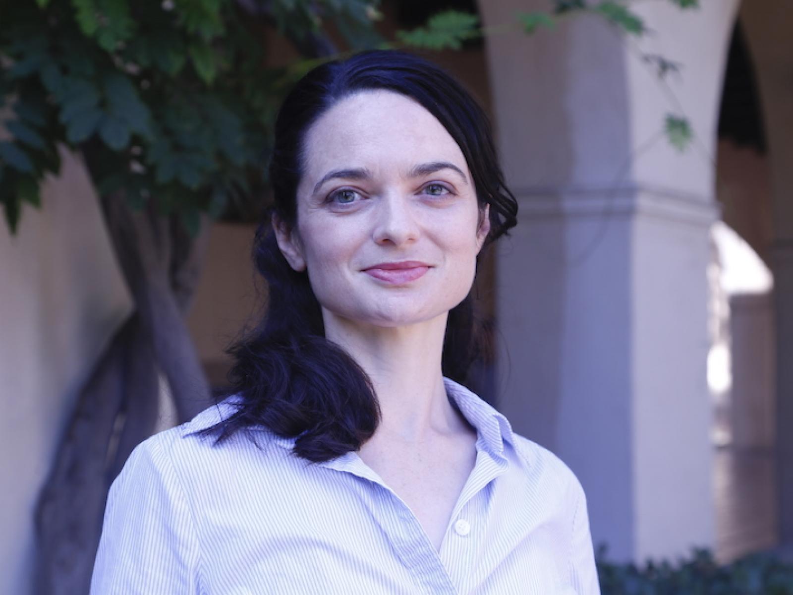 Photograph of a slightly smiling woman standing outside in business attire