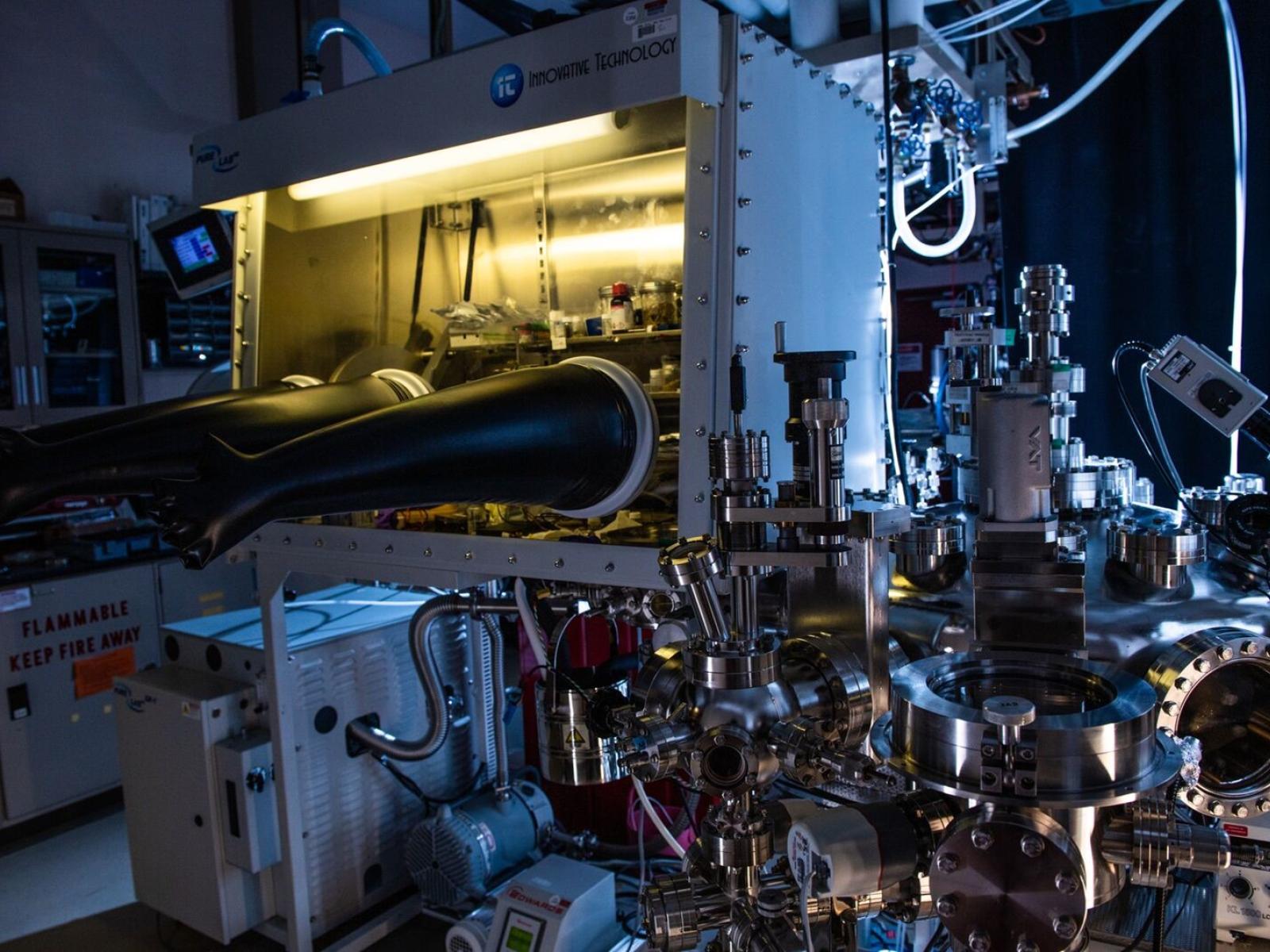 Photograph of a lit-from-within glovebox in a dark lab