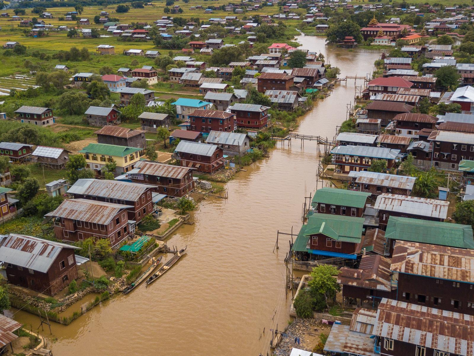 Photograph of muddy, flooded river by houses