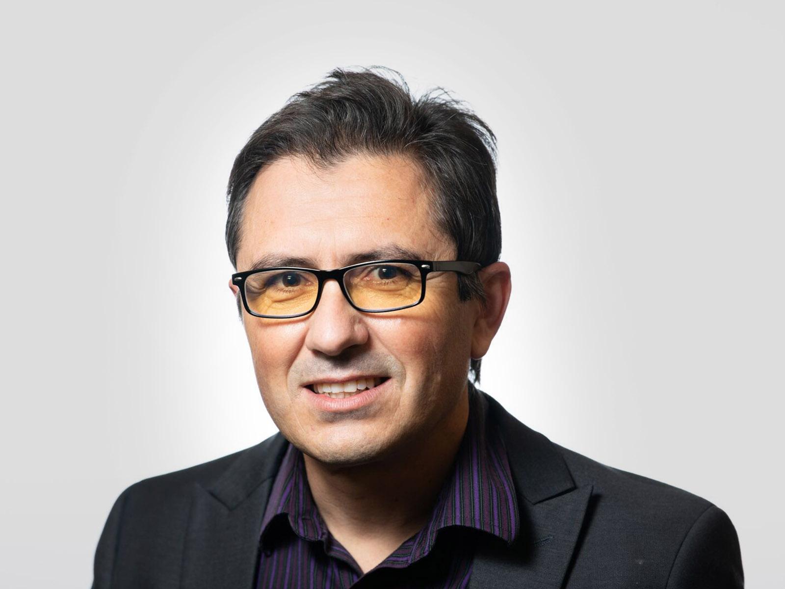 Man in glasses and dark shirt smiling