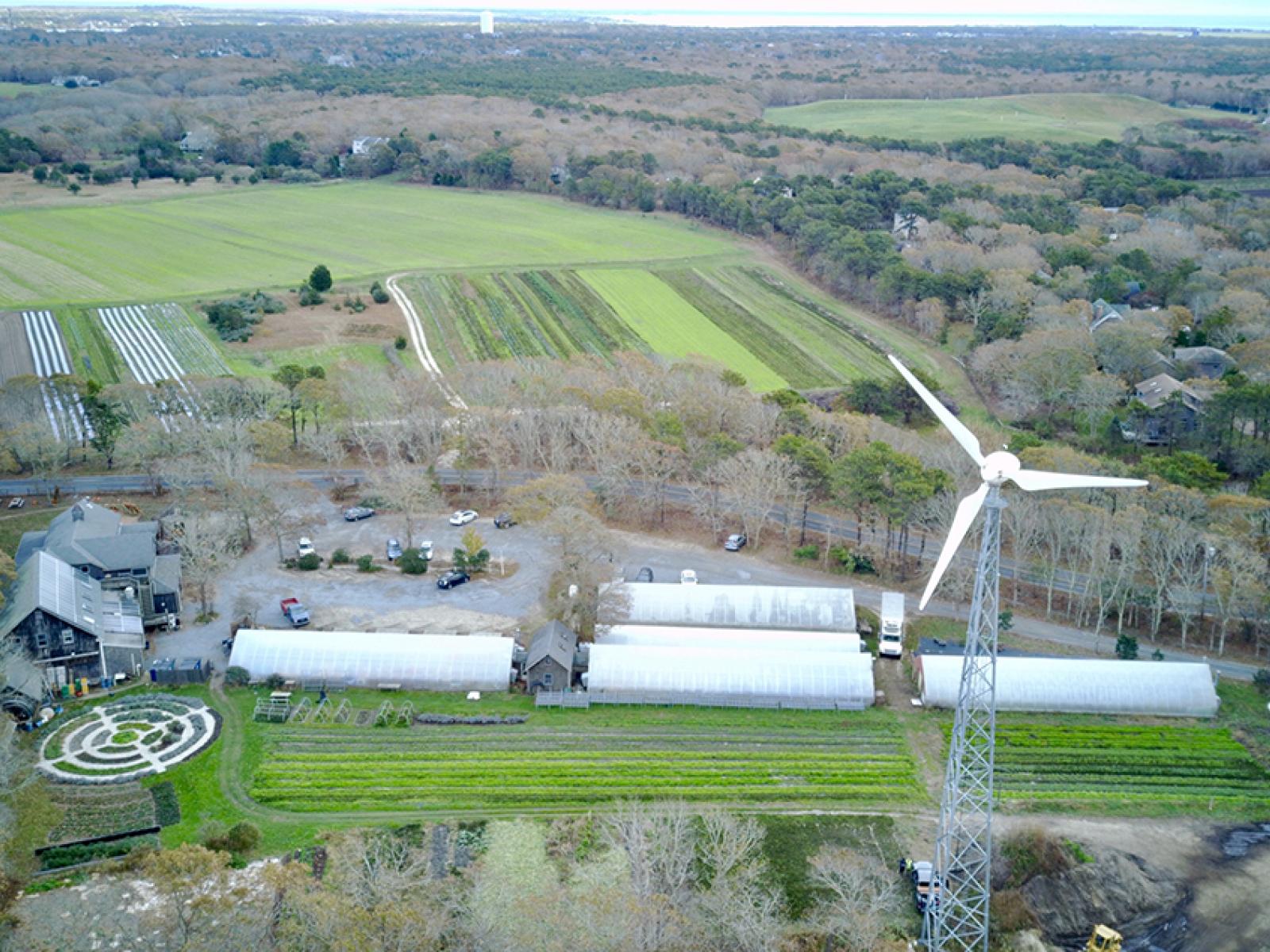 An aerial view of a small wind turbine with farmland in the background.
