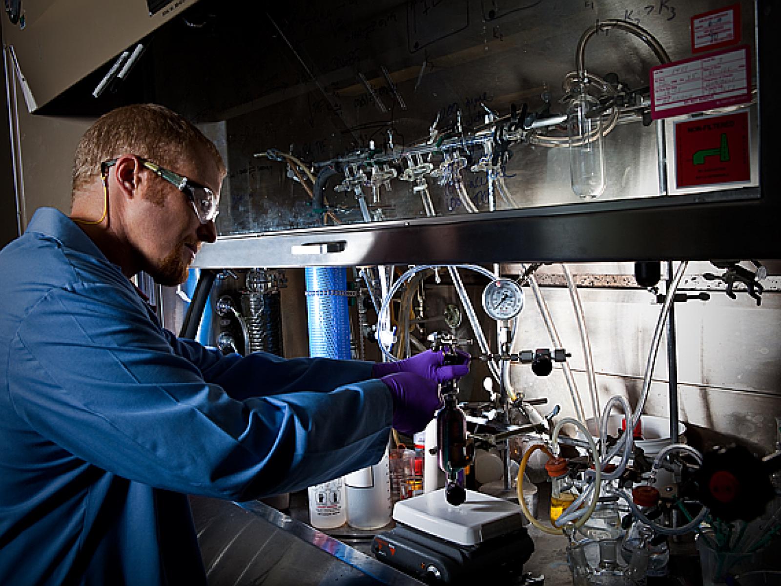 A man wearing a blue lab coat is using scientific equipment in a research laboratory