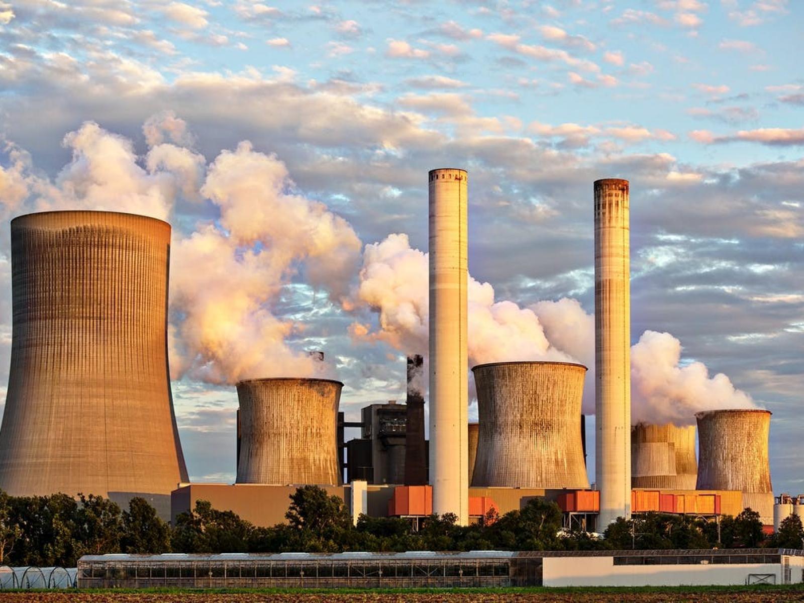 Chemical smokestacks releasing byproducts into the air on a clear day