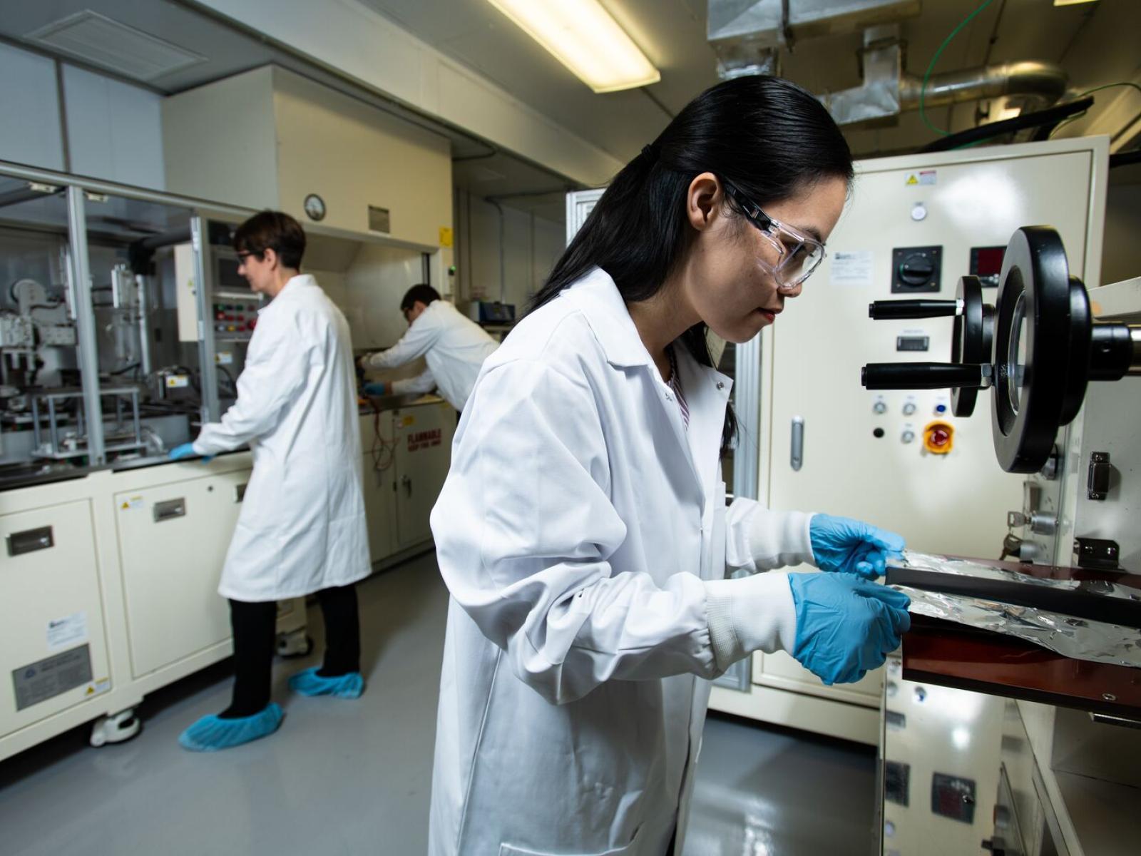 Photo of three researchers, dressed in safety gear, inside PNNL's Advanced Battery Facility