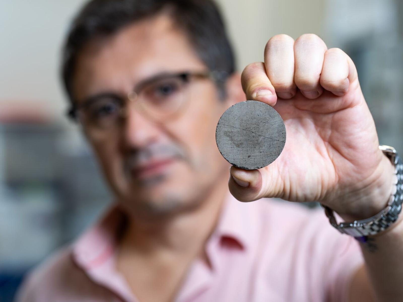 A PNNL researcher holding up a cylinder of cement made using algal biochar.
