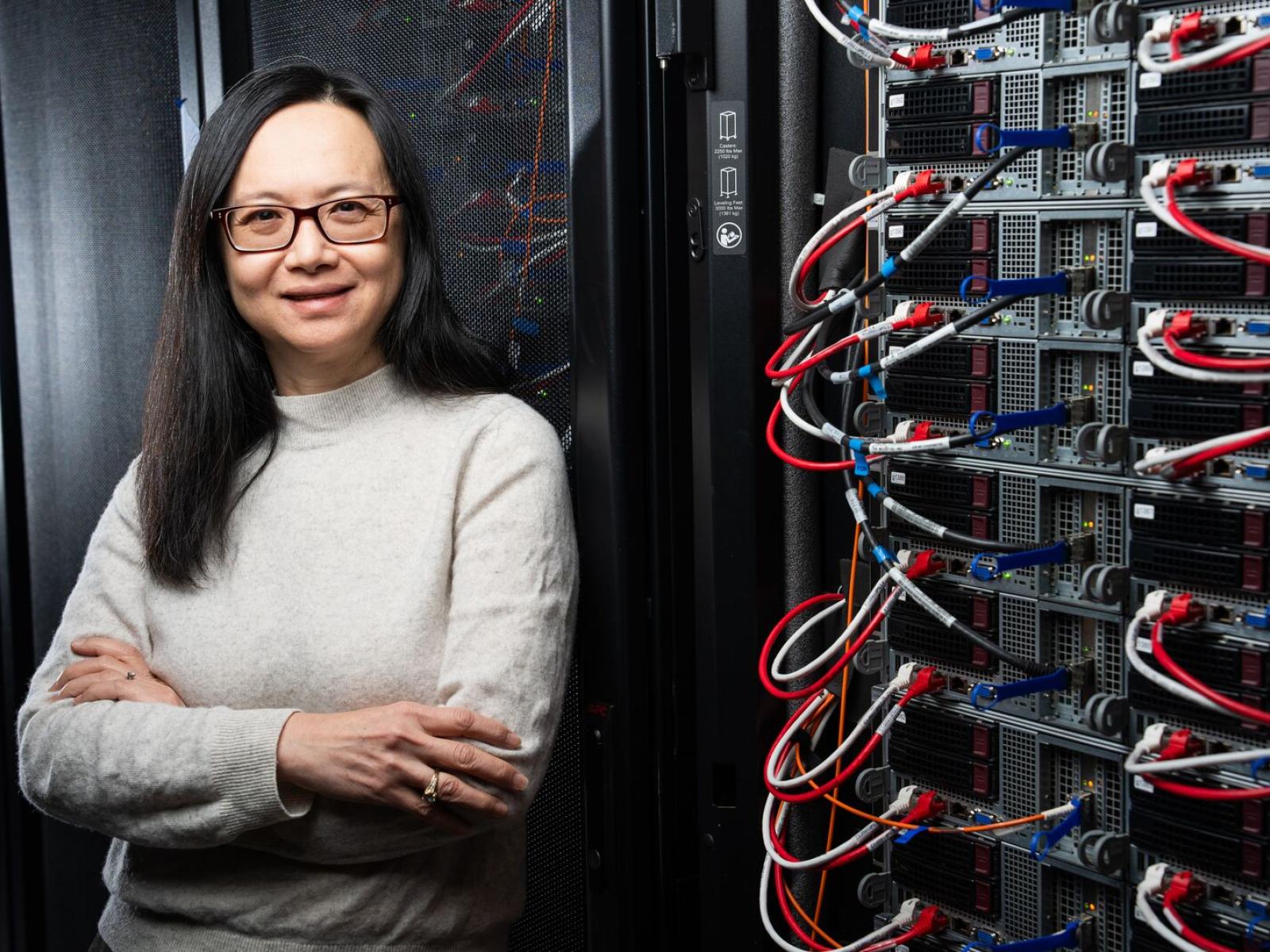 Margaret Cheung stands next to a wall of scientific instruments.