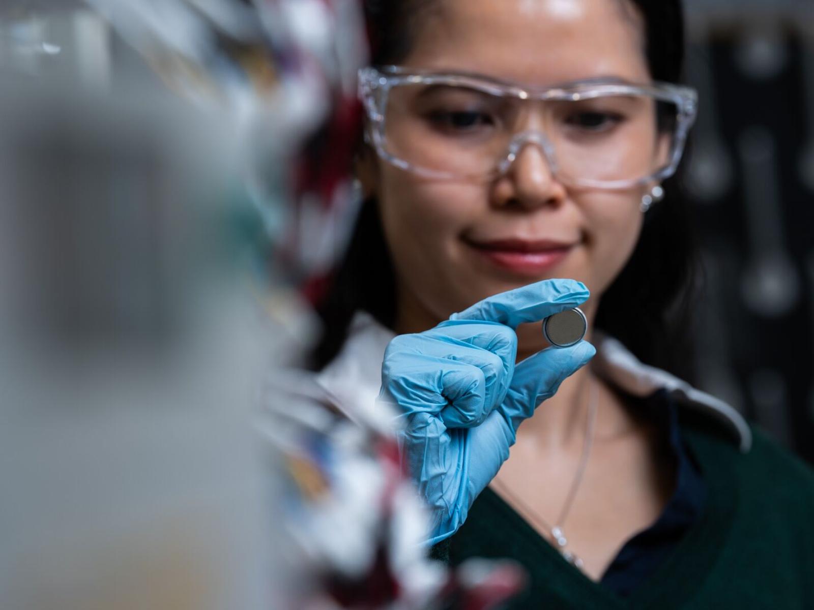 PNNL researcher Phung Le holds an experimental coin cell battery in her lab in the Grid Storage Launchpad.